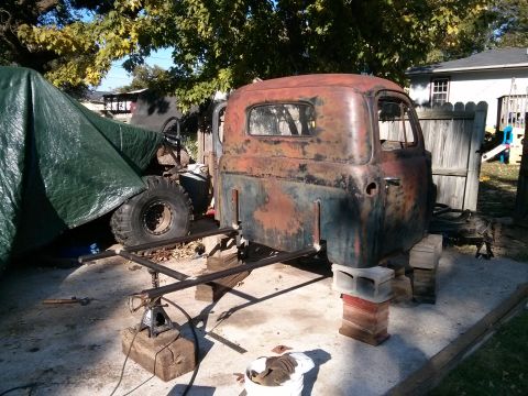 1986 Ford Bronco - Old truck cab undergoing restoration, supported by blocks and jack stands.