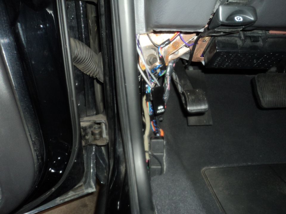 Car interior showing exposed wiring and pedals near the driver's side door jamb