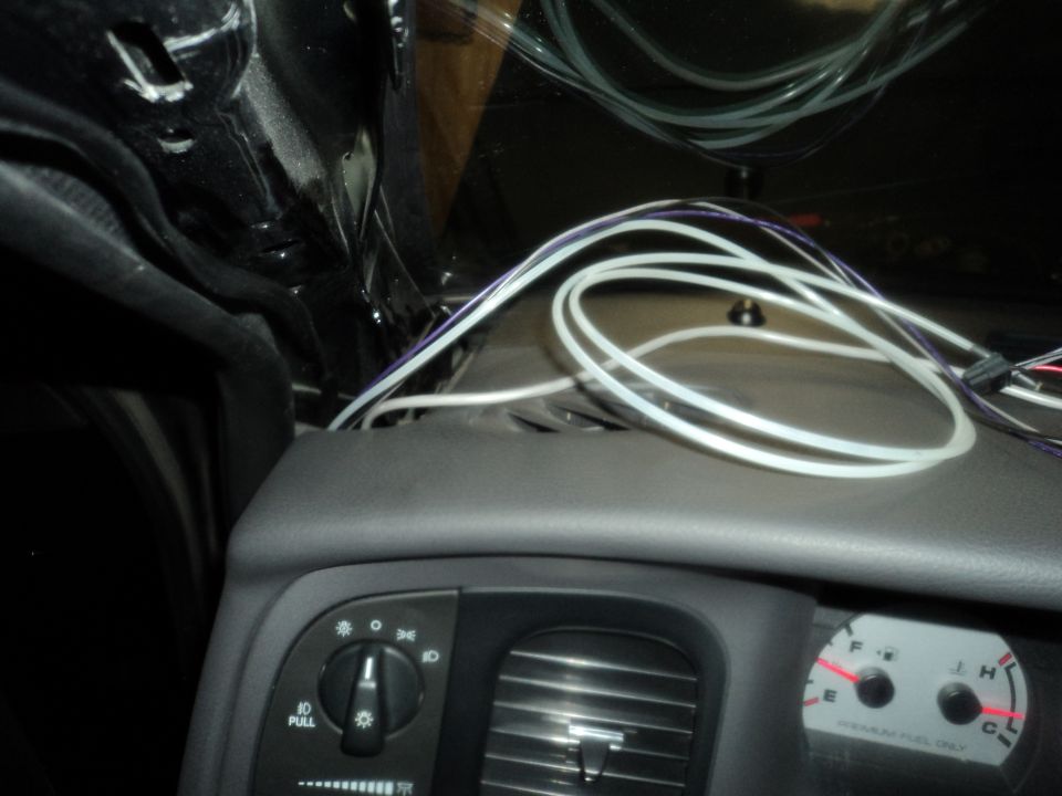 Car dashboard with lots of wires running above it. Shows headlight controls and part of the speedometer