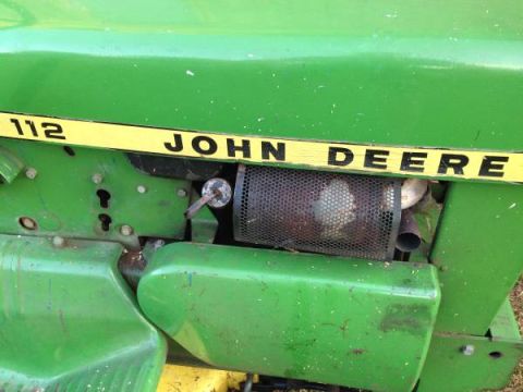 1982 Kubota RTV900 - Close-up of a John Deere 112 tractor's side panel, showing the exhaust and mesh screen.