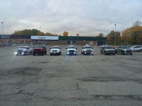 2006 Chevrolet Silverado 2500 - A group of pickup trucks are lined up in a parking lot in front of a retail store.