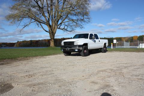 2006 Chevrolet Silverado 2500 - A white 2006 Chevrolet Silverado 2500 pickup truck is parked outdoors near a body of water under a clear blue sky.