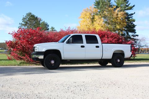 2006 Chevrolet Silverado 2500 - A white Chevrolet Silverado pickup truck is parked on a gravel road during autumn.
