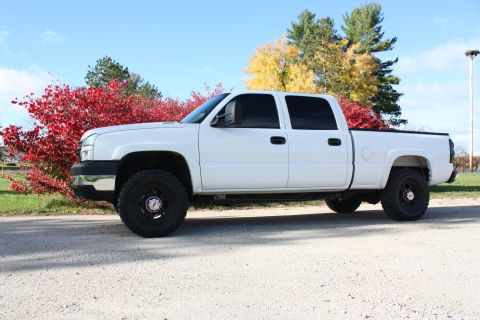 2006 Chevrolet Silverado 2500 - This 2006 Chevrolet Silverado 2500 pickup truck is shown from the side on a gravel road with autumn foliage in the background.