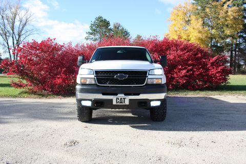 2006 Chevrolet Silverado 2500 - A white Chevrolet Silverado pickup truck is parked outdoors with red and yellow foliage in the background.