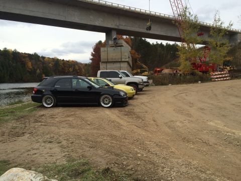 2006 Chevrolet Silverado 2500 - A silver pickup truck is parked on a dirt lot next to a black wagon and a yellow car, with a bridge overhead.