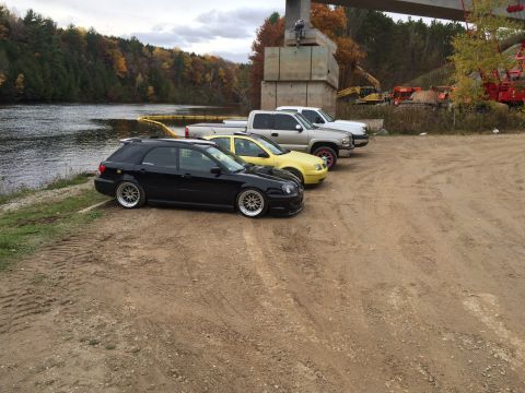 2006 Chevrolet Silverado 2500 - Four vehicles are parked on a dirt lot next to a river with a bridge under construction in the background.