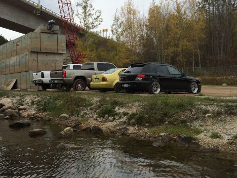 2006 Chevrolet Silverado 2500 - Several vehicles are parked near a body of water with a construction site in the background.