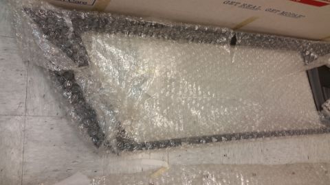 1987 Dodge 1500 - A part, possibly a mirror or window, is wrapped in bubble wrap and placed on a tiled floor.