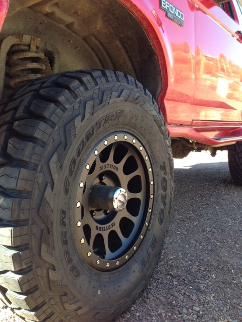 1996 Ford Bronco - A red 1996 Ford Bronco is shown from the side, focusing on the front wheel and fender area.