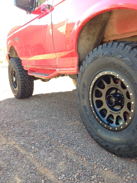 1996 Ford Bronco - This red 1996 Ford Bronco features aftermarket wheels and running boards, captured from a side profile.