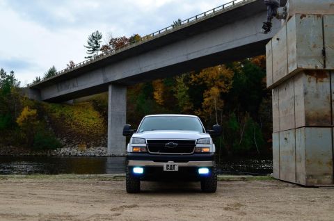 2006 Chevrolet Silverado 2500 - A 2006 Chevrolet Silverado 2500 is parked under a bridge with fall foliage in the background.