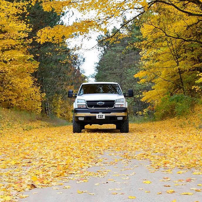 Front view of a 2006 Chevrolet Silverado 2500 parked on a road covered in yellow autumn leaves