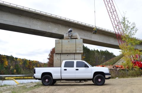 2006 Chevrolet Silverado 2500 - A white 2006 Chevrolet Silverado 2500 is parked near a bridge construction site with a crane visible in the background.