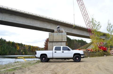 2006 Chevrolet Silverado 2500 - A white 2006 Chevrolet Silverado 2500 is parked near a river with a bridge construction project in the background.