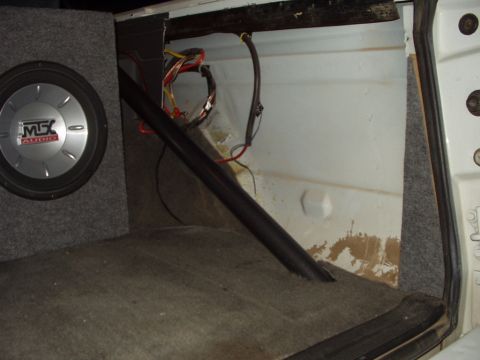 1993 Ford Bronco - The interior of a vehicle shows a subwoofer box and exposed wiring in the cargo area.