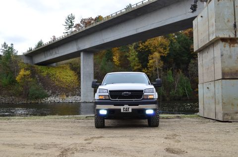 2006 Chevrolet Silverado 2500 - White Chevrolet Silverado truck parked near a river under a concrete bridge.