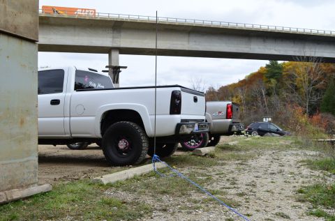 2006 Chevrolet Silverado 2500 - A white 2006 Chevrolet Silverado 2500 is parked under a bridge, showing its rear end and a pink ribbon decal on the back window.