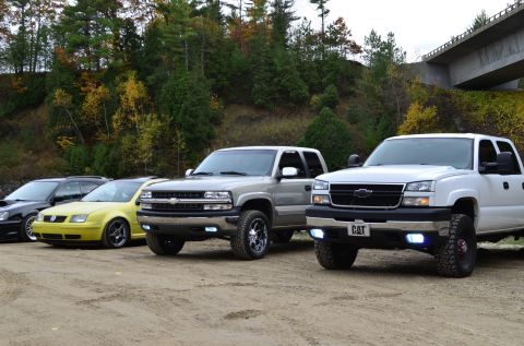 2006 Chevrolet Silverado 2500 - Two Chevrolet Silverado 2500 trucks are parked side-by-side with other vehicles in the background.