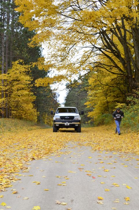 2006 Chevrolet Silverado 2500 - A white 2006 Chevrolet Silverado 2500 is seen from the front on a rural road during autumn, with fallen leaves blanketing the ground.