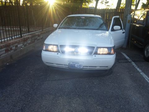 2000 Mercury Grand Marquis - A white Mercury Grand Marquis is parked outside with its front doors open and headlights illuminated.