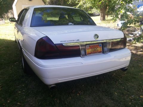 2000 Mercury Grand Marquis - The rear of a white 2000 Mercury Grand Marquis LSE is shown parked on grass with a shed in the background.