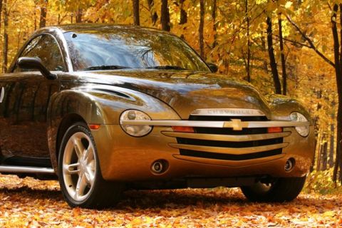 2006 Chevrolet Silverado 2500 - A Chevrolet SSR is parked in a wooded area during autumn, surrounded by fallen leaves.