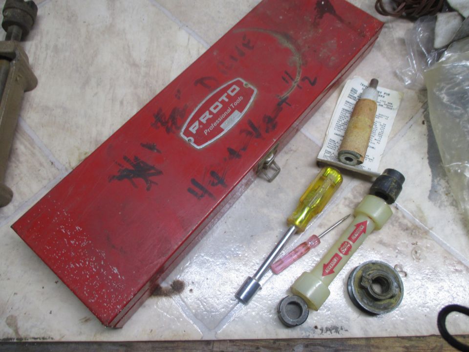Red Proto Professional Tools metal box with screwdrivers, a filter, and other small parts