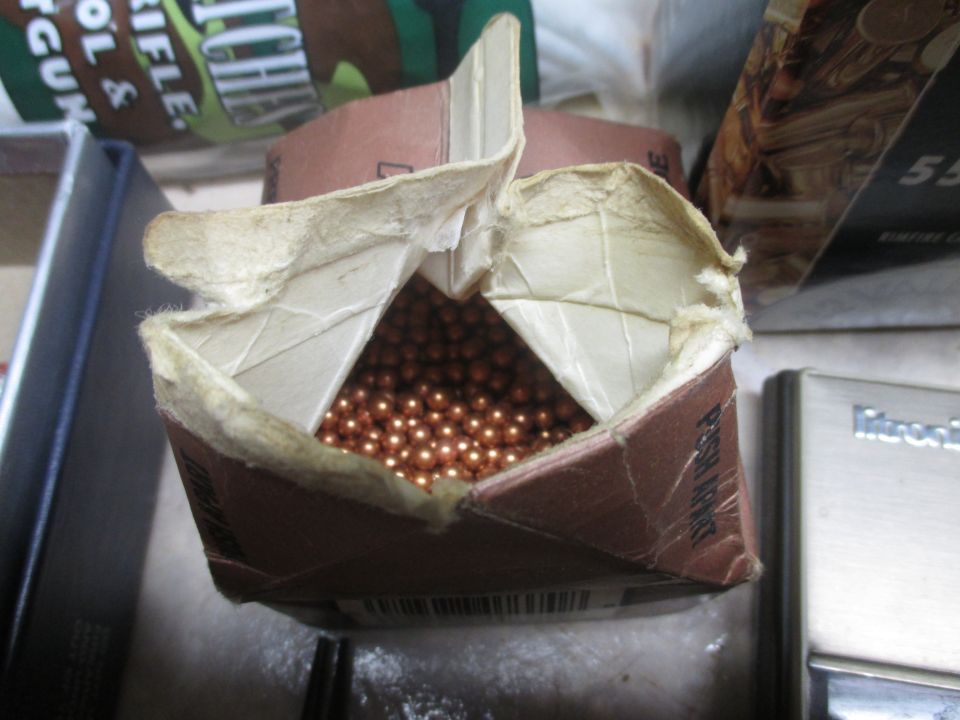 Open cardboard box filled with BBs, next to a silver device with "Mitronix" visible