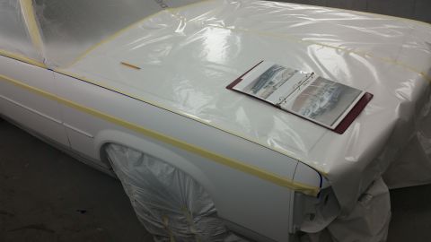1991 Ford LTD Crown Victoria - A car is covered in plastic sheeting and tape, with a photo binder resting on its hood.