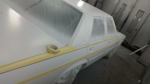 1991 Ford LTD Crown Victoria - A white car is prepared for painting, with protective coverings and tape applied to its body panels.