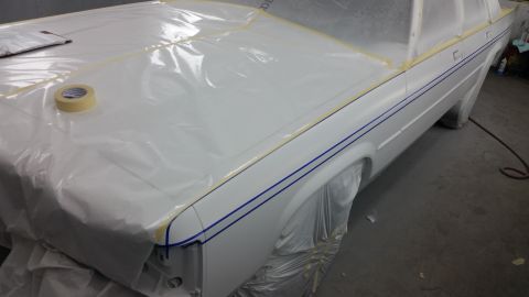 1991 Ford LTD Crown Victoria - A white sedan is prepped for painting, with plastic sheeting and masking tape applied to its body panels.