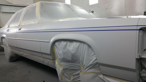 1991 Ford LTD Crown Victoria - A 1991 Ford Crown Victoria is prepped for paint in a spray booth, with protective coverings on the wheels and windows.