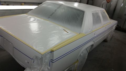 1991 Ford LTD Crown Victoria - A white sedan is being prepped for painting, with plastic wrap covering most of the body.
