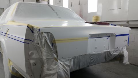 1991 Ford LTD Crown Victoria - A car is being prepped for painting inside a booth, with protective coverings on its body panels.