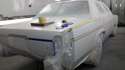 1991 Ford LTD Crown Victoria - A white 1991 Ford Crown Victoria LTD is prepped for painting, with plastic sheeting and masking tape covering most of its body.