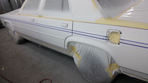 1991 Ford LTD Crown Victoria - A white sedan is being prepped for painting, showing its side profile with blue pinstripes.