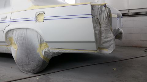 1991 Ford LTD Crown Victoria - A white 1991 Ford Crown Victoria LTD is prepared for painting, with its rear quarter panel taped and covered.