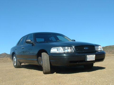 1998 Ford Crown Victoria - dark green Ford Crown Victoria sedan parked on a dirt overlook under a clear blue sky.