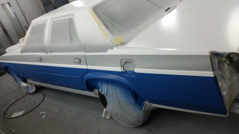 1991 Ford LTD Crown Victoria - A car is being prepped for painting, with protective coverings on its windows and wheels.