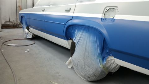 1991 Ford LTD Crown Victoria - A two-tone blue and white sedan is being prepped for paint, with its wheels covered in protective plastic.
