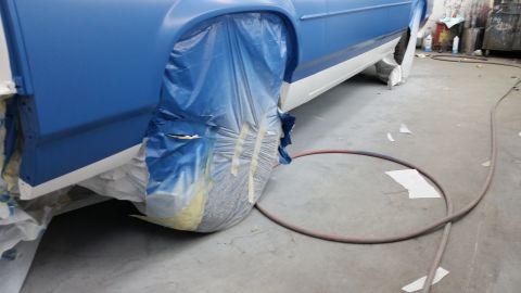 1991 Ford LTD Crown Victoria - Car body undergoing painting in a workshop, with wheels covered for protection.