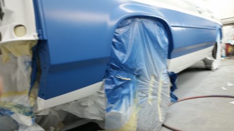 1991 Ford LTD Crown Victoria - A car is being prepped for painting, with blue plastic covering the wheels and lower body panels.