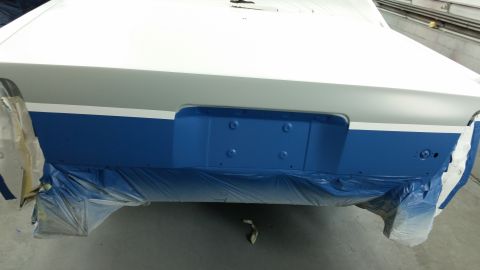1991 Ford LTD Crown Victoria - The rear of a car is being prepped for painting, with blue plastic sheeting covering the lower section.