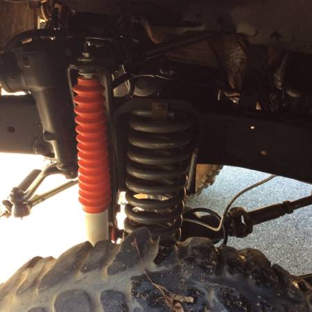 1979 Ford Bronco - Close-up of a vehicle's front suspension system, showing a coil spring and shock absorber.