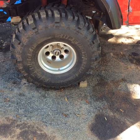 1979 Ford Bronco - Close-up of a large off-road tire and red fender on a vehicle.