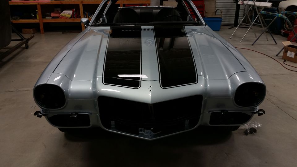 Front view of a silver 1970 Chevrolet Camaro with black racing stripes on the hood and roof