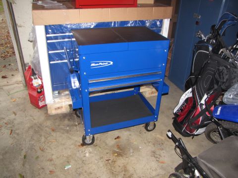 1992 Ford F-150 - A blue tool cart is parked on a concrete floor next to golf bags and a red gas can.