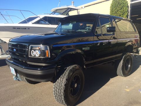 1992 Ford Bronco - A black 1992 Ford Bronco SUV is parked next to a white boat.