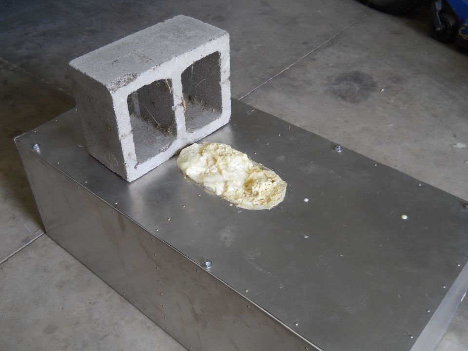 Cinder block sits on a metal box with a blob of foam next to it